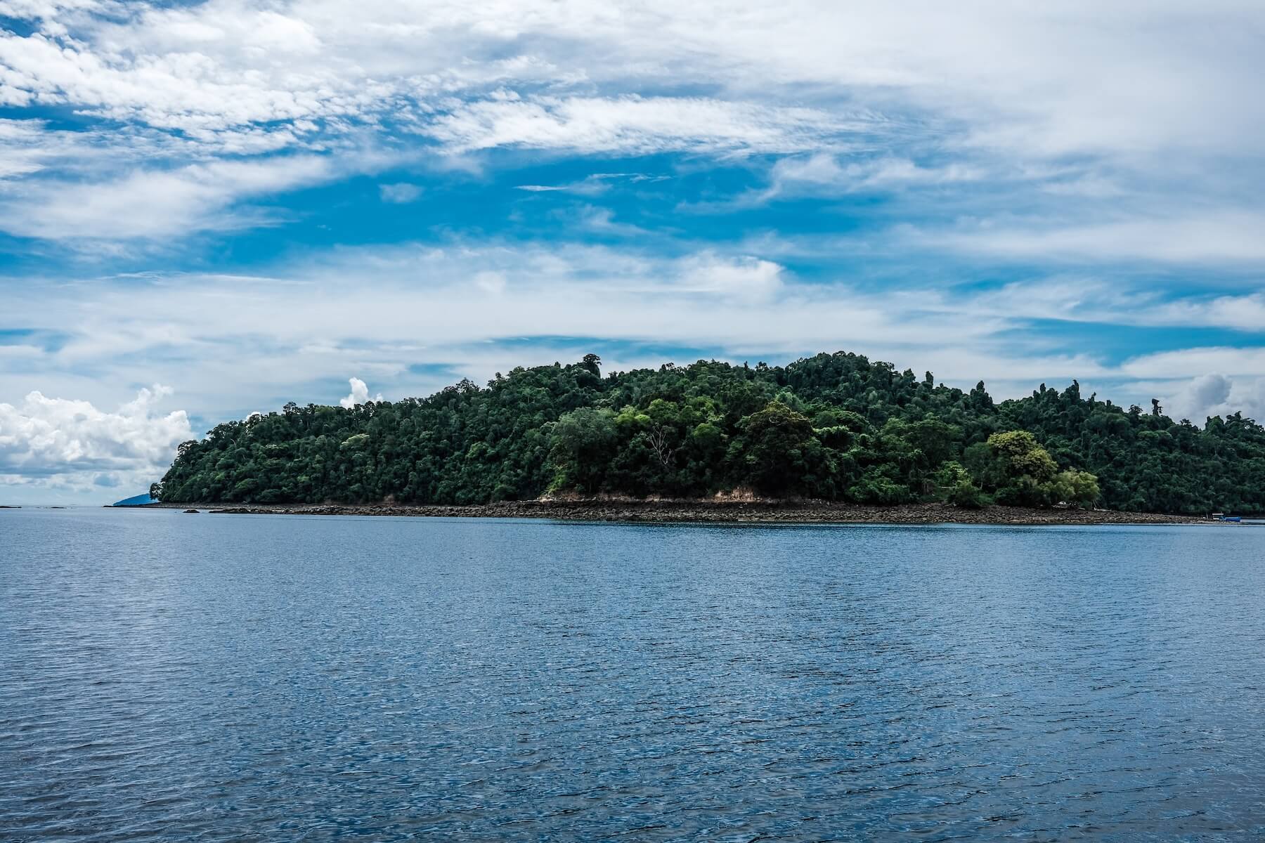 The island after editing: a green forest, blue sky and blue sea.